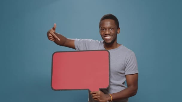 Adulto feliz apontando para bolha de fala de papelão em estúdio — Vídeo de Stock