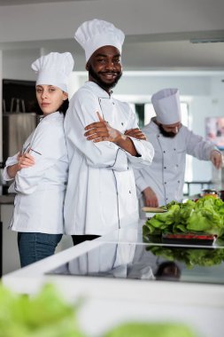 Restoran mutfağında kameraya poz verirken kolları çapraz duran çok ırklı gastronomi uzmanları..