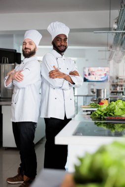 Mutfak uzmanlarının portresi aşçı şapkası takıyor ve yemek masasının yanında duruyor..
