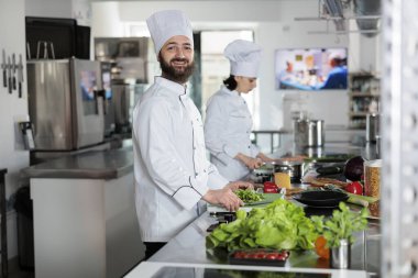 Profesyonel restoran mutfağında kameraya bakarken gülümseyen baş aşçının portresi..