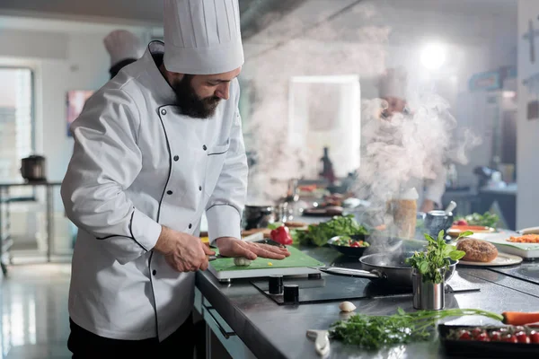 Jefe de cocina con cuchillo de cocina profesional para aplastar una gran cabeza de ajo orgánico fresco que se añadirá al plato gourmet. —  Fotos de Stock