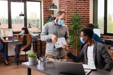 Pazarlama istatistiklerini karşılaştıran çok ırklı işadamları