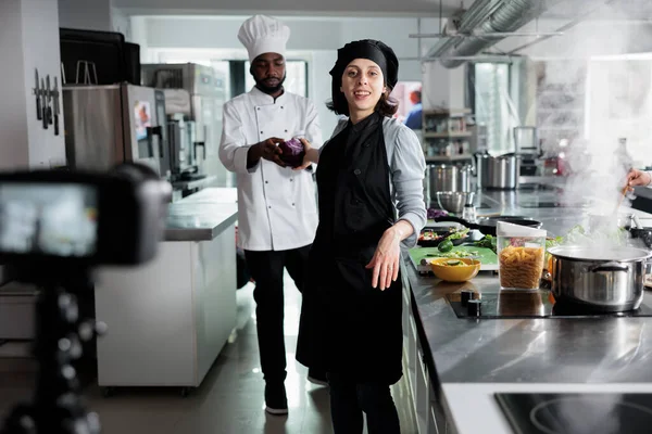 Aşçıbaşı, gurme yemek pişirirken aşçı yardımcısından yardım alırken yemek pişirme seansını kaydediyor..