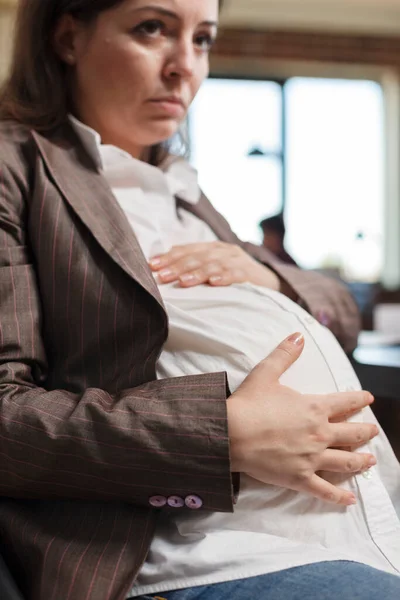 Blisko kobiety w ciąży dotykającej brzucha w biurze agencji. — Zdjęcie stockowe