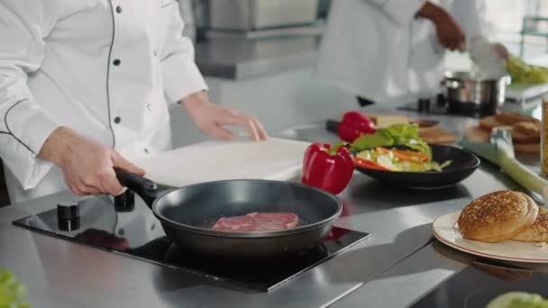 Cozinheiro masculino preparando carne de porco na frigideira com azeite — Vídeo de Stock