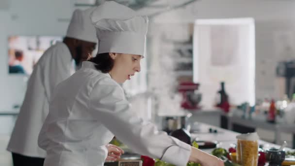 Jonge vrouw koken voedsel recept met knoflookteentje op keukenfornuis — Stockvideo