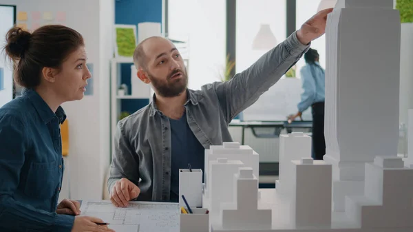 Hombre y mujer trabajando juntos para diseñar un plan de planos, mirando el modelo de edificio — Foto de Stock