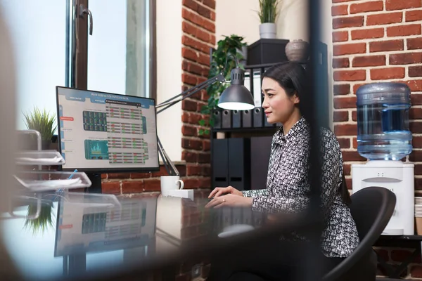 Jovem mulher de negócios confiante revisando gráficos de status do projeto de inicialização enquanto está sentado no escritório moderno. — Fotografia de Stock
