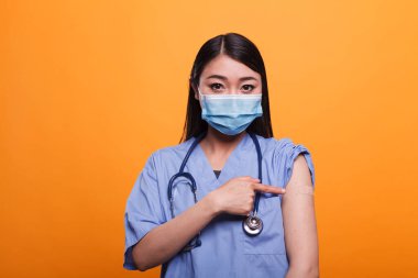 Sorumlu bakıcı, insanları bağışıklık kazanmaları için teşvik ederken yara bandı takıyor.