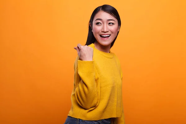 Hermosa mujer atractiva mostrando gesto de dinero en efectivo en el día de pago mientras sonríe de todo corazón sobre fondo naranja. — Foto de Stock