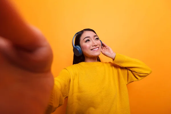 POV van vrolijke charmante influencer het dragen van een koptelefoon en het luisteren naar muziek nemen selfie — Stockfoto