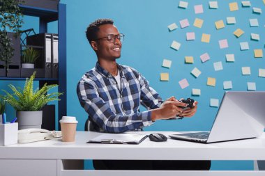 Mutlu gülümseyen ofis çalışanı ve modern oyun kontrolörü iş yerinde eğlenirken video oyunları oynuyorlar..