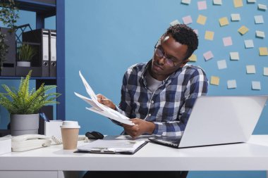 Genç yetişkin girişimci finansal belgeleri ve proje yönetim çizelgelerini analiz ediyor