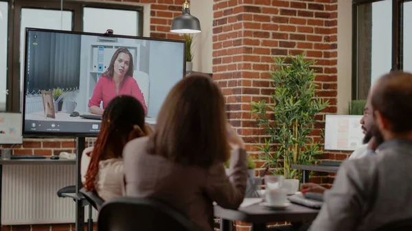 Різноманітна команда колег використовує відеоконференцію, щоб спілкуватися з жінкою — стокове фото