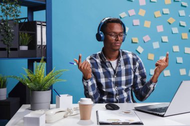 Zen, müzik çalarken kablosuz kulaklık takan Afro-Amerikan ofis çalışanı.
