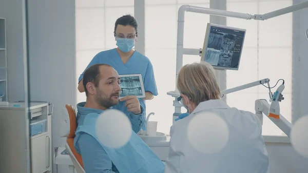 歯痛患者に歯x線スキャンを示す歯科チーム — ストック写真