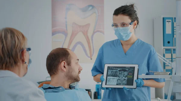 Verpleegkundige en patiënt analyse kunstgebit radiografie in tandheelkunde kabinet — Stockfoto