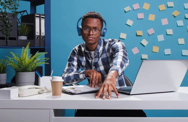 Neşeli başlangıç proje yöneticisi kulaklık takıyor, belge panosu var