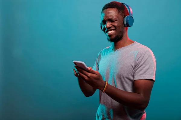 Millennial guy using smartphone and enjoying music on headphones — Stock Photo, Image