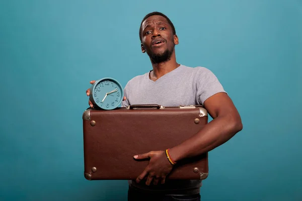 Retrato del tipo sosteniendo la maleta retro y el reloj delante de la cámara —  Fotos de Stock