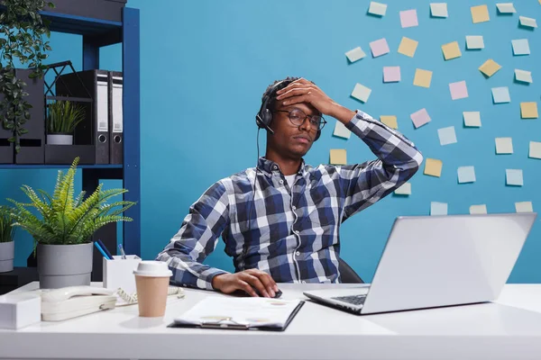 Müder und gestresster Kundenbetreuer mit Kopfschmerzen im Telefongespräch mit potenziellen Kunden. — Stockfoto