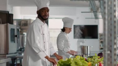 Kamera karşısında kollarını kavuşturarak poz veren kendinden emin bir aşçının portresi.