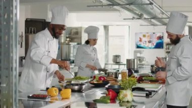 Erkek aşçı tavaya sebze koyuyor.