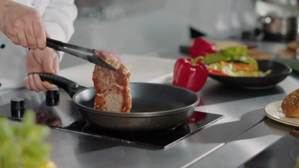 Chef profesional cocinando carne de cerdo en sartén en la estufa — Vídeos de Stock