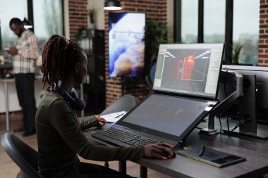 Oyun geliştiricisi oyun seviyesini tasarlarken yaratıcı ajans ofis çalışma alanında oturuyor.