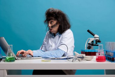 Delinin teki olan çılgın biyokimyacı laboratuvar patlaması ile ilgileniyor. Masada oturuyor ve kimyasal deney raporlarını inceliyor..