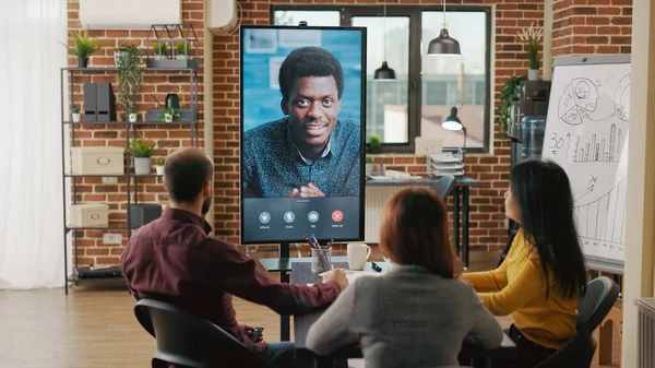 Group of workers using remote video call to talk to man — Foto Stock