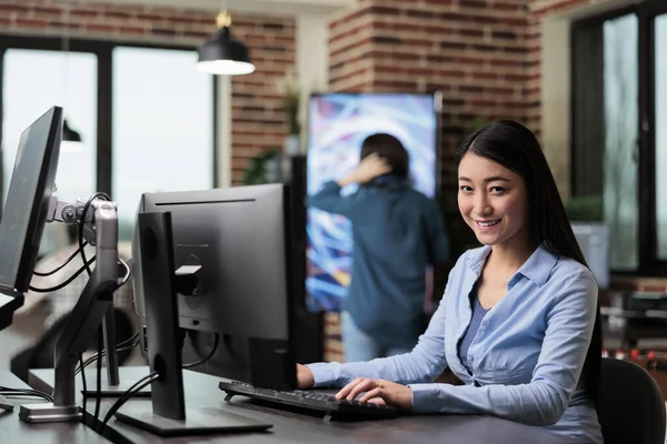 Χαμογελώντας 3D καλλιτέχνης και προγραμματιστής κάθεται στο γραφείο στο χώρο εργασίας γραφείο, ενώ εργάζονται σε νέο έργο παιχνίδι. — Φωτογραφία Αρχείου