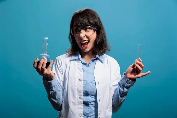 Ürkütücü görünüşlü biyokimya uzmanı elinde kimyasal sıvı örnekleriyle dolu cam şişeler tutuyor. — Stok fotoğraf