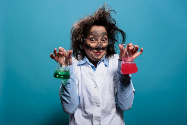 Mad scientist with dirty face and messy hair having beakers filled with liquid substances after failed laboratory experiment.