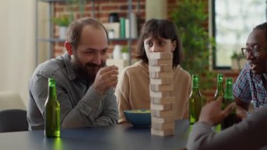 Pozitif insanlar oturma odasında Jenga masası oyunuyla eğleniyorlar.