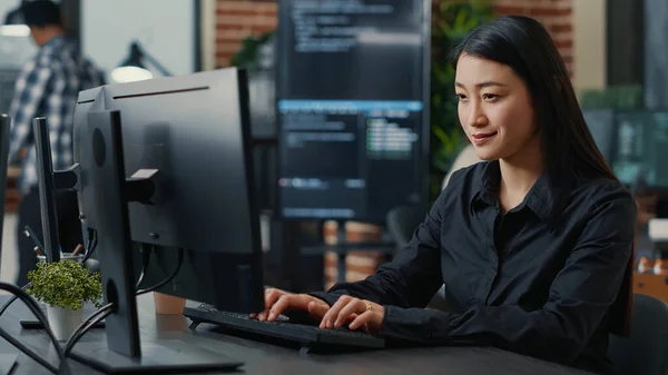 Portrait of smiling asian programer focused on writing code sitting at desk — Stock Photo, Image