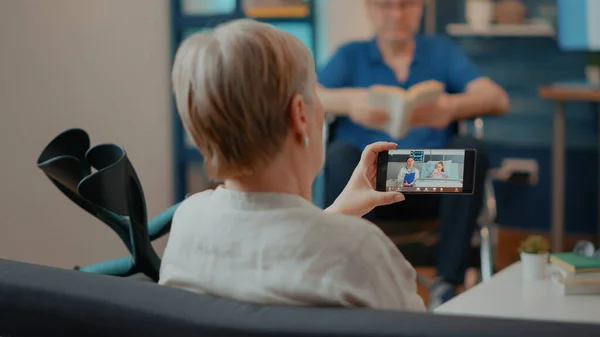 Oude vrouw met krukken met behulp van video-oproep op mobiele telefoon — Stockfoto