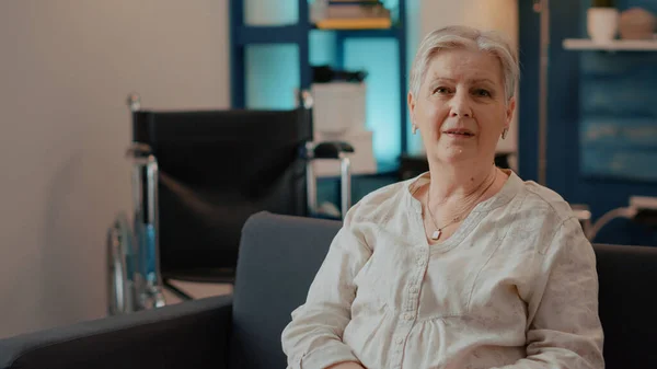 Portrait of elderly woman looking at camera in living room — Stock Photo, Image