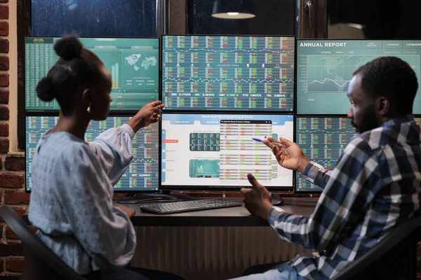 Африканские американские финансовые консультанты рассматривают данные и статистику рынка в режиме реального времени с целью продажи акций. — стоковое фото