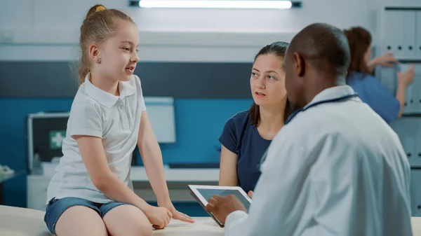 Pequeño niño discutiendo con el médico masculino en el examen — Foto de Stock