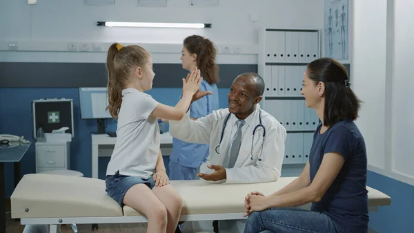 Amistoso médico dando highfive a niño alegre en visita de chequeo — Foto de Stock