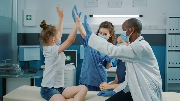 Веселая медсестра и медик дают пять малышу — стоковое фото