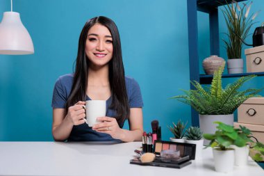 Çekici Asyalı etkileyici kameraya gülümseyen ve güzellik dersi kaydeden