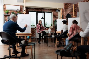 Kıdemli öğretmen çizim tekniğini çok ırklı sanat öğrencilerine açıklıyor.