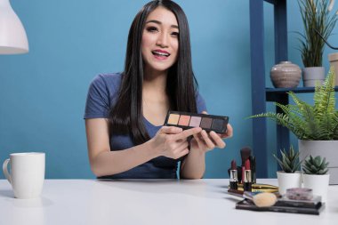 Asyalı vlogger elinde makyaj paleti ile yaratıcı öğretim videosu çekiyor