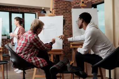 Çizim tekniğini açıklayan resim öğretmeni denetleyici öğrenci.