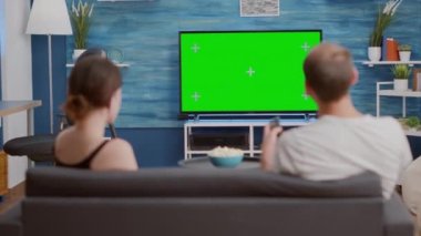 Bir erkeğin yeşil ekranda televizyon kanallarına göz atarak kız arkadaşının en sevdiği programı aramasının arka planı