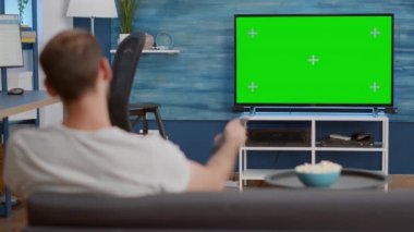 Televizyondaki yeşil ekrana bakarken insanın kanal değiştirdiği statik tripod görüntüsü.