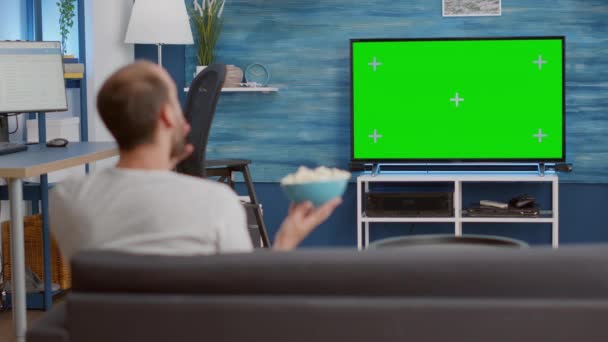 Hombre comiendo palomitas de maíz del tazón mientras ve el programa de televisión favorito en la pantalla verde — Vídeo de stock