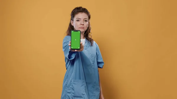 Портрет професійного лікаря, що тримає смартфон, смс та показує дизайн макетів зеленого екрану — стокове фото